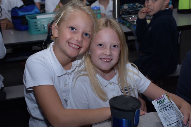 Two smiling girls at the lunch table