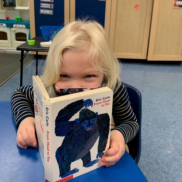 Preschool student reading a book during Before Care